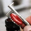A New York Hook Keychain Bottle Opener in use popping a cap.