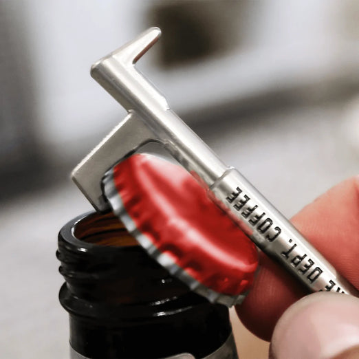 A New York Hook Keychain Bottle Opener in use popping a cap.